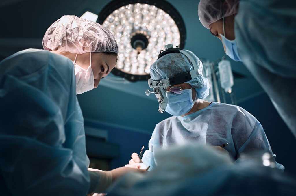 Medizinisches Team im Operationssaal, dunkler Hintergrund. Das Theater des Operationssaals, ein internationales Team von professionellen Ärzten in einem modernen Operationssaal führt eine Operation durch. Leben retten, moderne Medizin, blaues Blaulicht