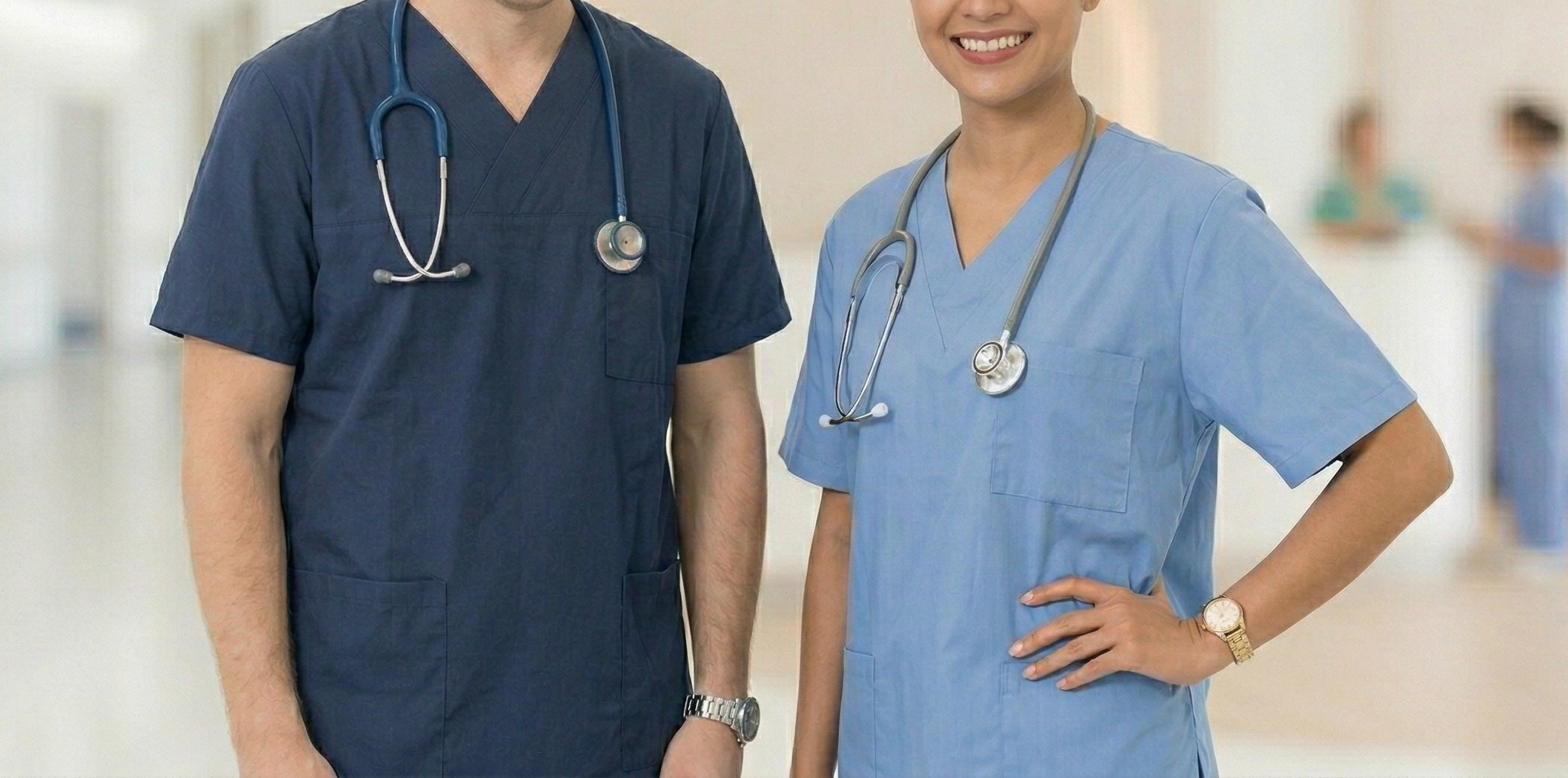 Zwei lächelnde Personen in blauer Arbeitskleidung mit Stethoskopen im Krankenhaus